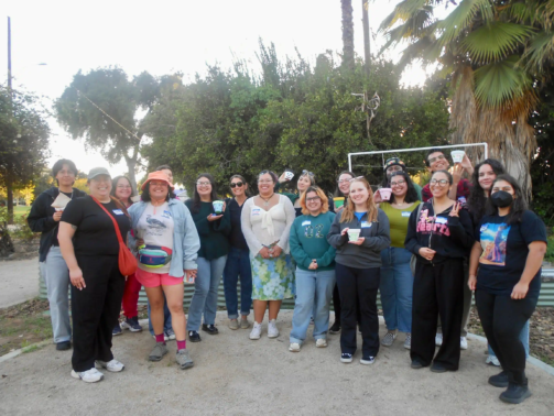 a group of 20 mostly young people holding personalized plant potters in a garden